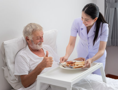 caregiver serving food to elderly man