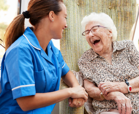 senior woman and caregiver laughing together