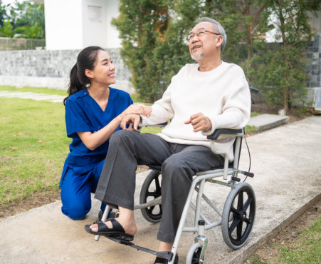 senior man in a wheelchair with carer outdoors