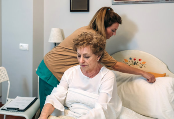 caregiver preparing the bed of an elderly woman