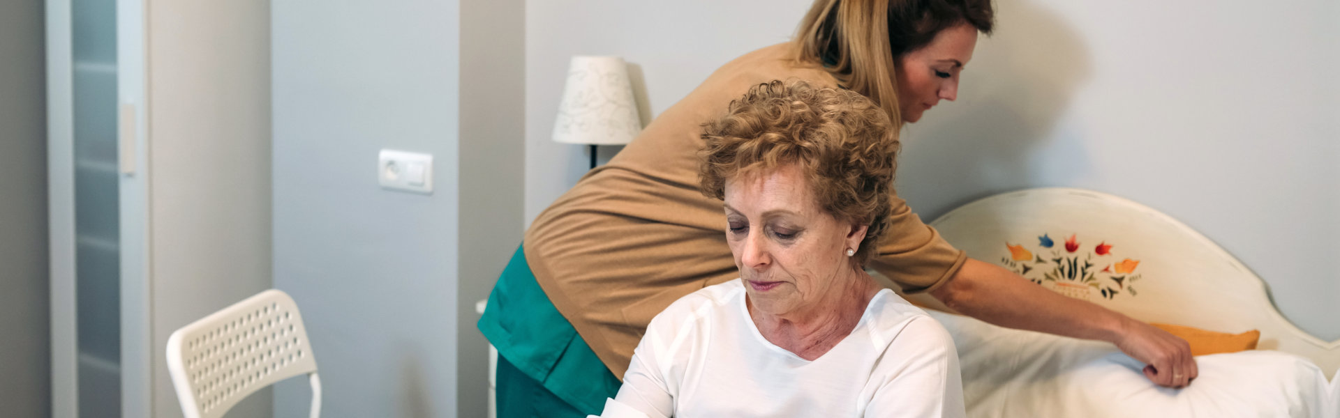 caregiver preparing the bed of an elderly woman